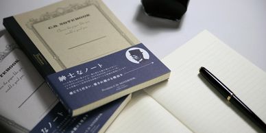 Classic notebooks with a pen placed on an open lined notebook.