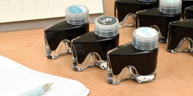 Unique ink bottles shaped like eyeglasses on a desk.