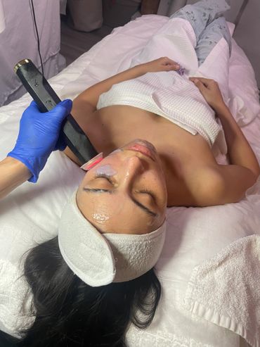 Woman receiving a facial treatment with a handheld device on her cheek.