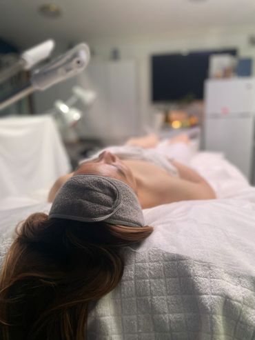 Person lying on a spa bed with a gray eye mask, relaxing.