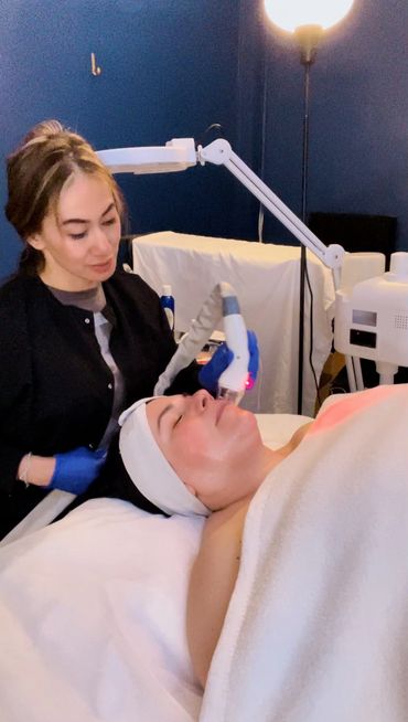 A skincare professional performs a facial treatment with a high-tech device on a relaxed client.