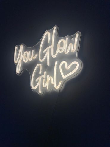 Neon sign glowing with the words 'You Glow Girl' and a heart symbol.
