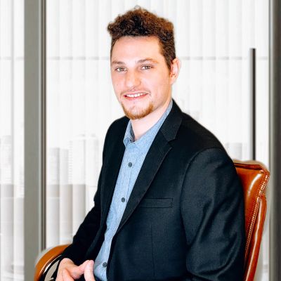 Smiling man in a black blazer sitting on a chair.