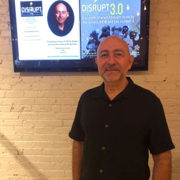 Man standing in front of a screen displaying a DISRUPT 3.0 poster.