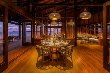 Elegant wooden dining area with ocean view at sunset.