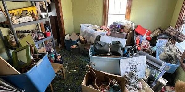 Cluttered room filled with boxes, bags, and miscellaneous items scattered around.