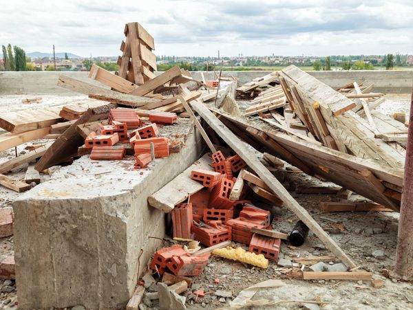 Construction site with scattered bricks and wooden beams.