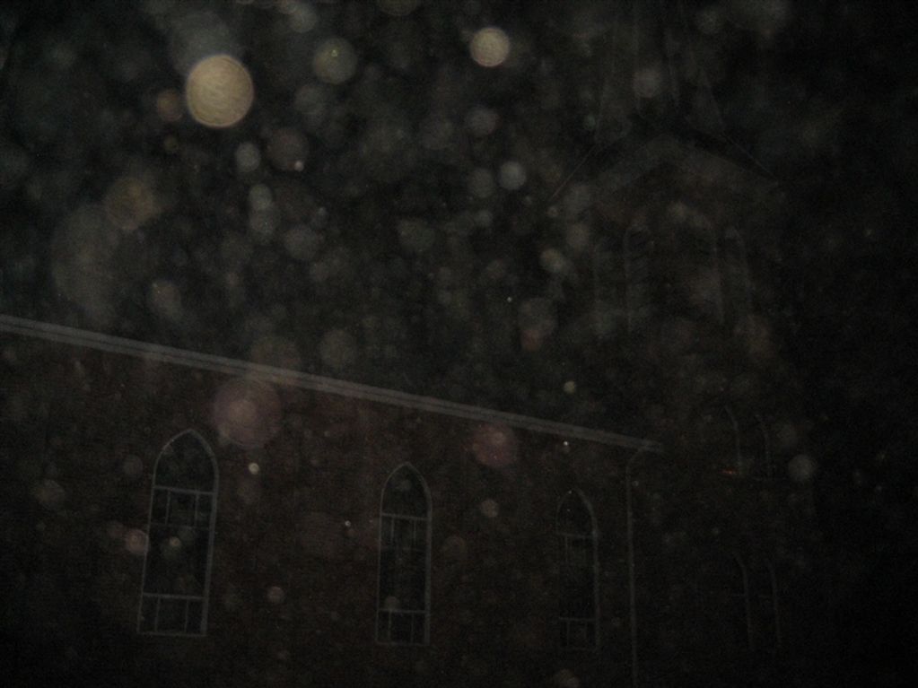 A church building with a cloud of orbs in front of it ranging in size and brightness
