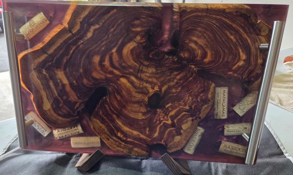 Wooden slab table with embedded wine corks and metal handles.