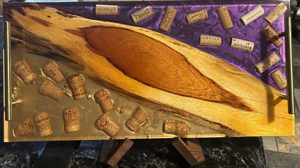 Wood and resin serving tray with embedded wine corks and metal handles.