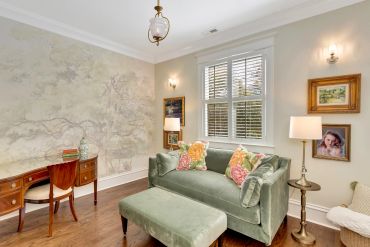 Cozy reading room with green velvet sofa and wooden desk.