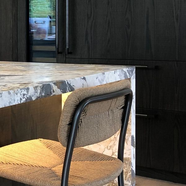 Modern kitchen with a large marble island and bar stools.