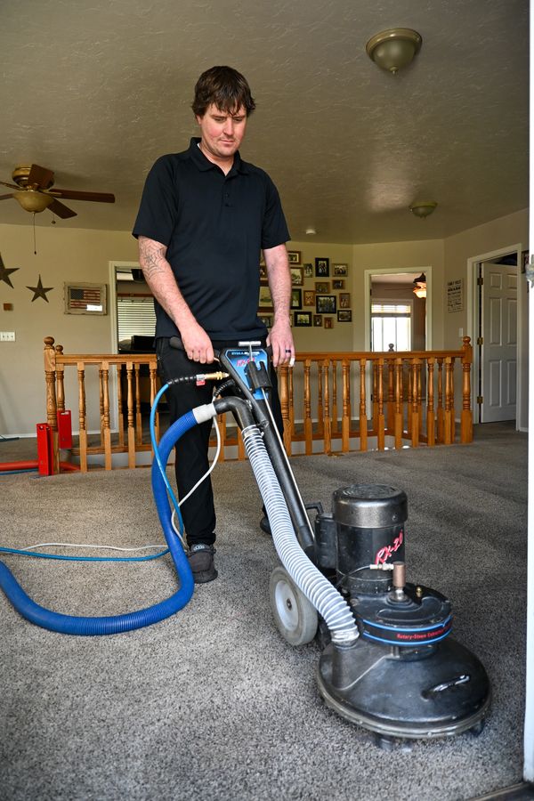 Man cleaning carpet with a professional machine in a home.
