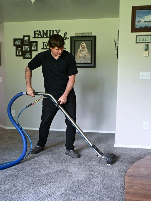 Man cleaning carpet with professional vacuum in a living room.