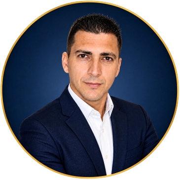 Confident man in dark suit and white shirt against blue background.