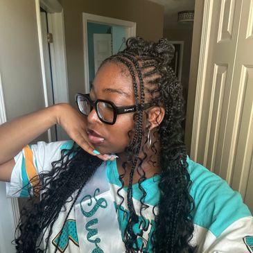 Young woman with braided and curly hair posing indoors.