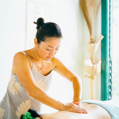 A woman giving a relaxing back massage in a bright room.