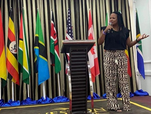 Woman speaking at a podium with multiple international flags behind her.