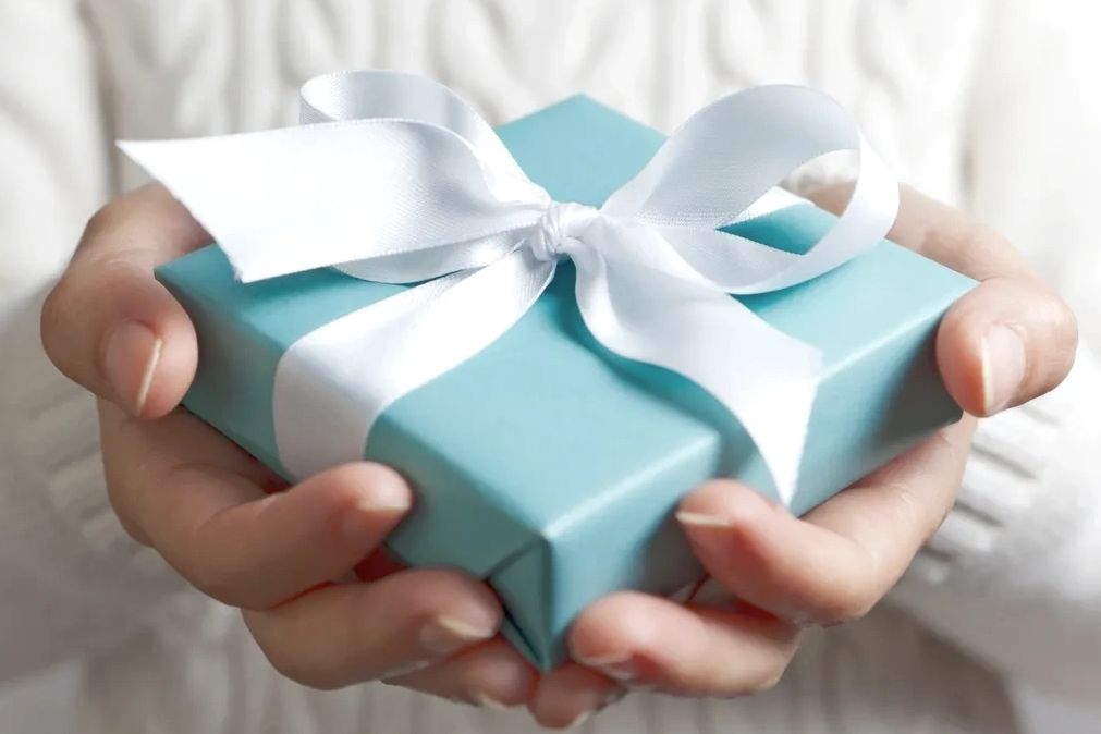 Woman's hands giving a small gift box