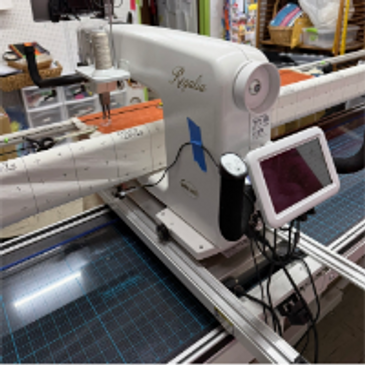 Longarm quilting machine set up with a touchscreen and quilting frame.