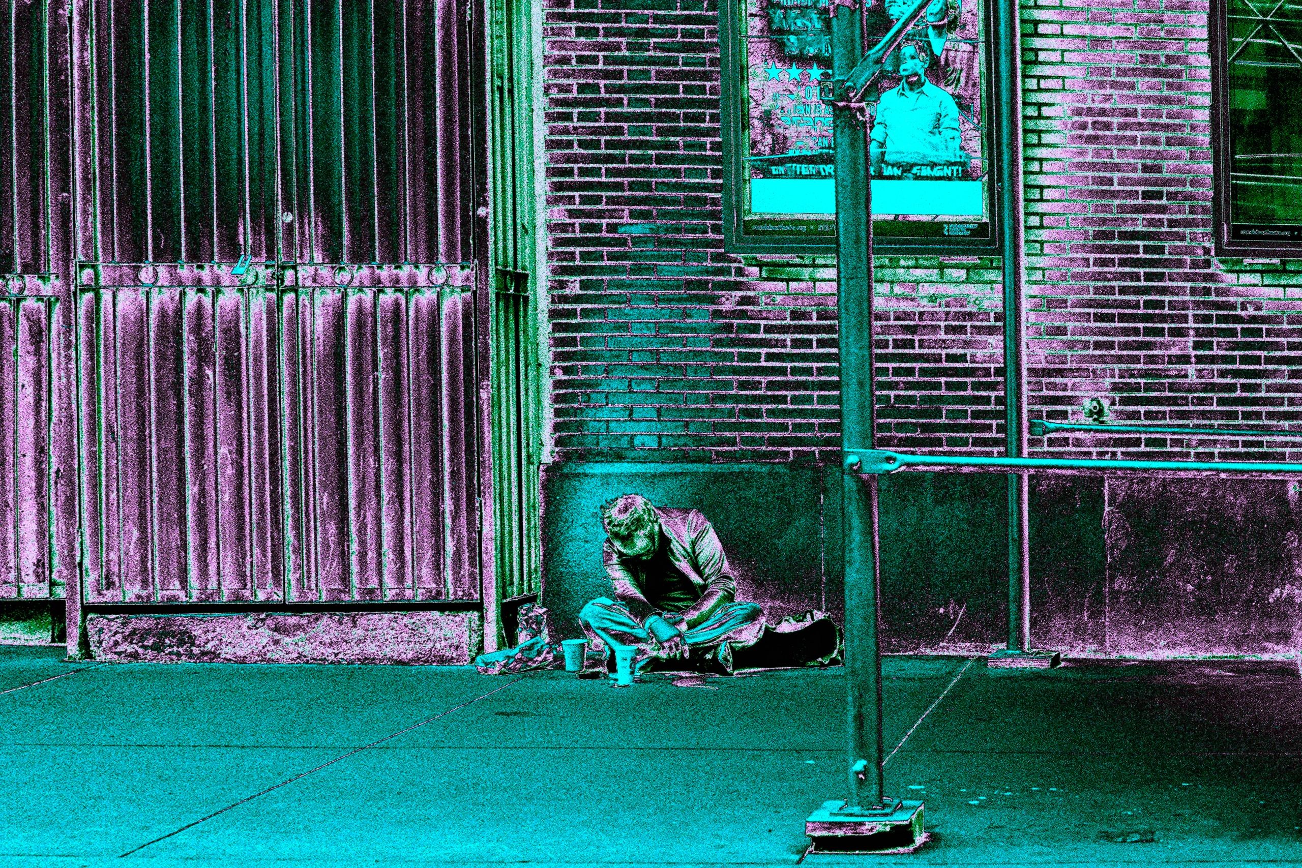 A man sits on the ground, barely able to keep himself up. This image is in hypercolor.