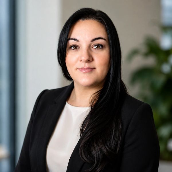 Professional woman in black blazer with neutral expression.