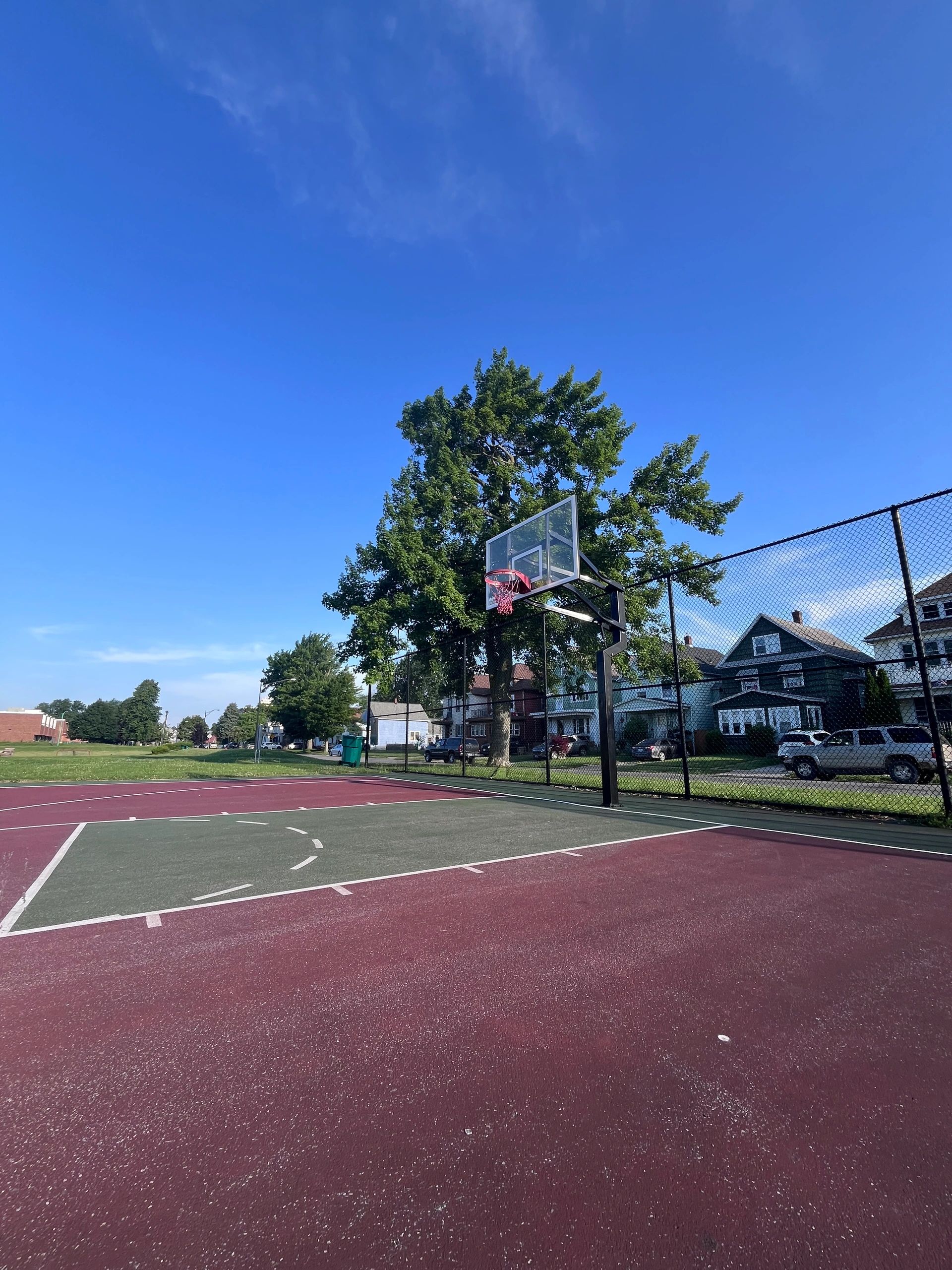 Empty outdoor basketball court under clear blue sky.