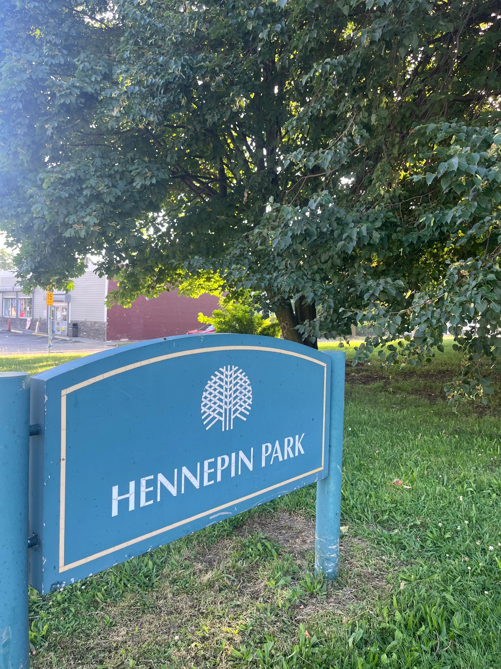 Sign indicating Hennepin Park with trees and greenery.