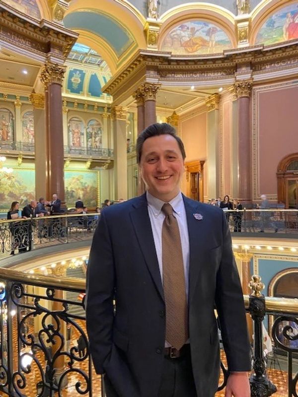 Man in a suit smiling inside an ornate building.