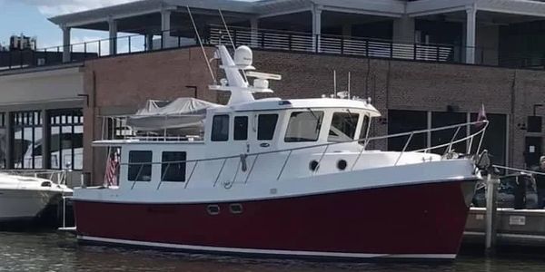 A red and white boat docked by a waterfront building under a partly cloudy sky.