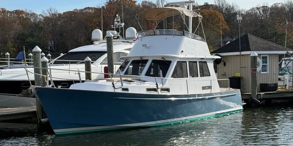 A blue and white motor yacht docked at a marina on a calm day.