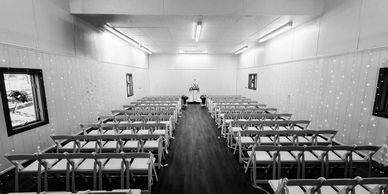 Empty wedding ceremony room with decorated chairs and a central aisle.