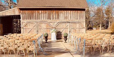 Rustic barn wedding setup with wooden chairs and floral decorations.