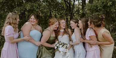 A joyful bride with her bridesmaids outdoors, sharing laughter and happiness.