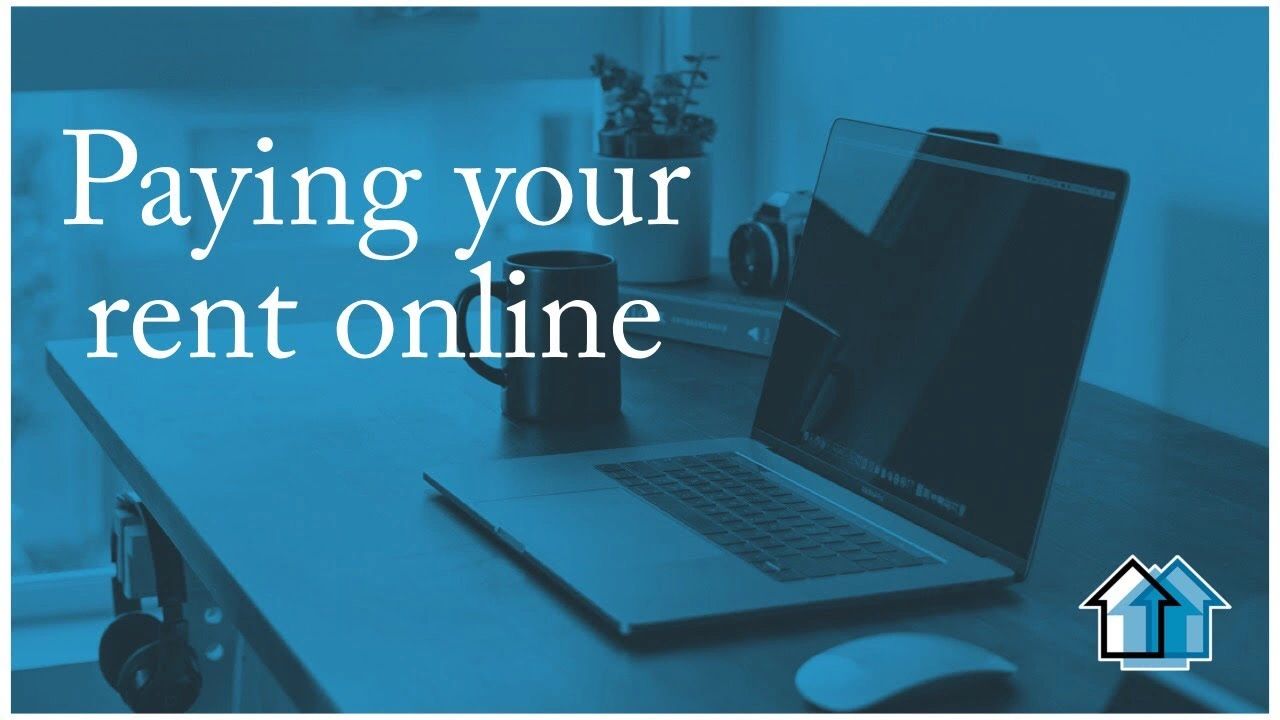 Laptop on a desk with text about paying rent online.