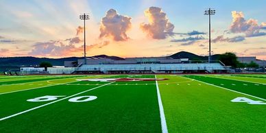 Football field at sunset with dramatic clouds.