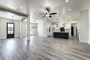 Spacious modern open-concept kitchen and living area with gray wood flooring.