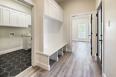 Bright hallway with built-in bench and hexagonal tile laundry room.