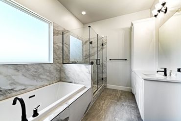 Modern bathroom with marble accents, a bathtub, and glass shower.
