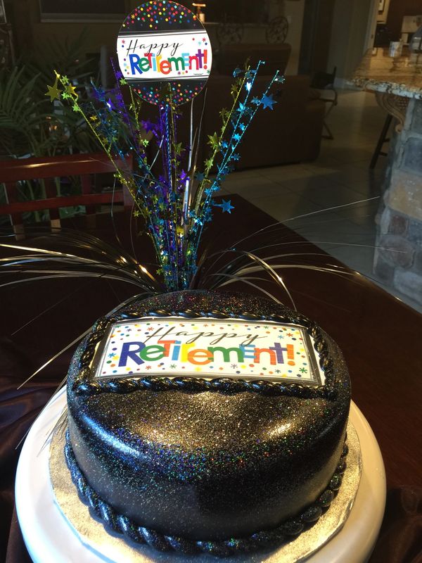 black cake with happy retirement banner and celebration spray