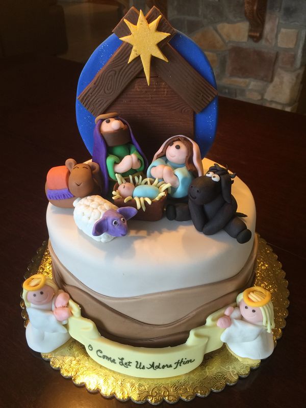 Cake with nativity scene on top and 2 angels on the s