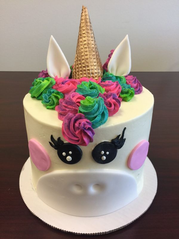 unicorn cake with fondant facial features multicolored rosette mane white ears and gold horn