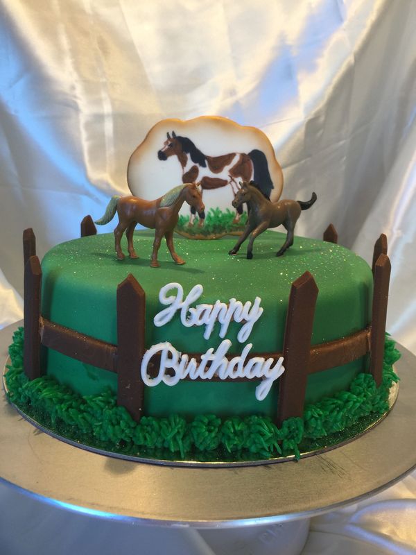 green cake with brown fence on the side and horses on top