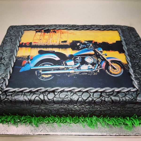 Gray cobblestone sheet cake with colorful motorcycle on top.