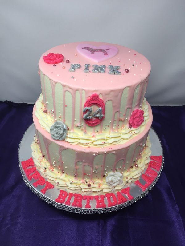 white cake with pink drip, and pink logo and pink roses