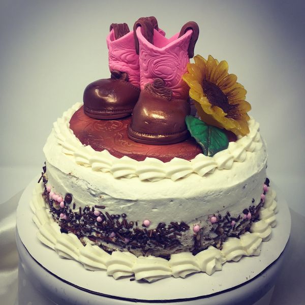 white cake with cowboy boots and sunflower on top