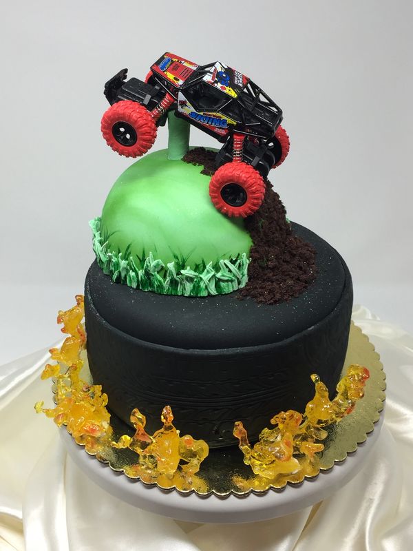 2 tier black cake with flames on the bottom and monster toy truck on the top
