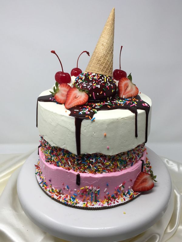 pink and white cake with ice cream cone tipped over and chocolate dripping down the sides 