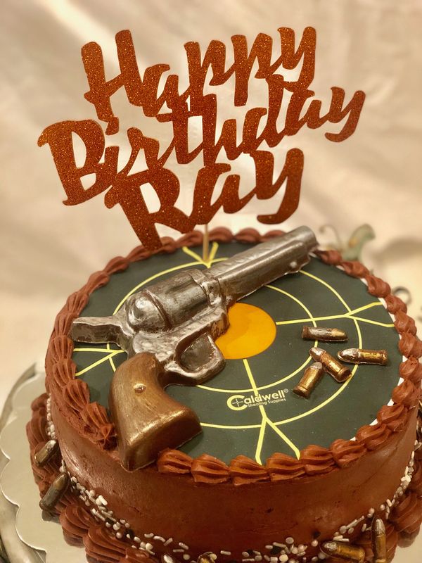 Brown cake with green target on top with revolver and ammo