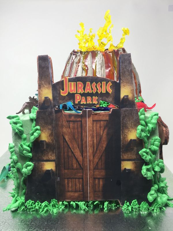 Jurassic Park cake with gate on the side and volcano with flames on top